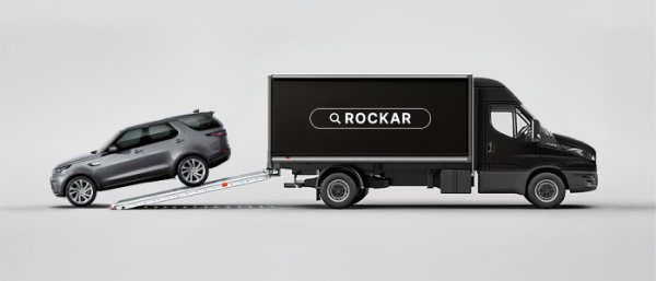 Side view of a Rockar delivery truck with a Discovery being delivered from the back.