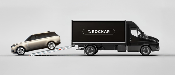 Side view of a Rockar delivery truck with a Range Rover being delivered from the back.