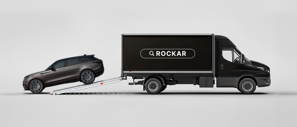 Side view of a Rockar delivery truck with a Velar being delivered from the back.