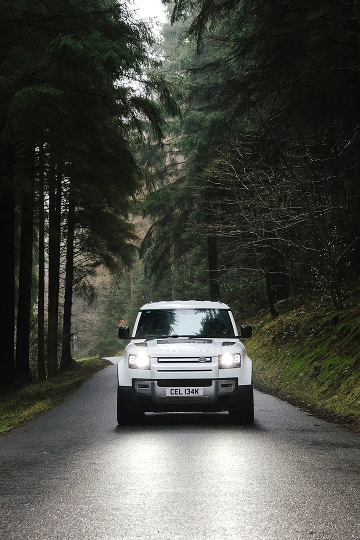 Front-view of a white Range Rover, surrounded by woodland.