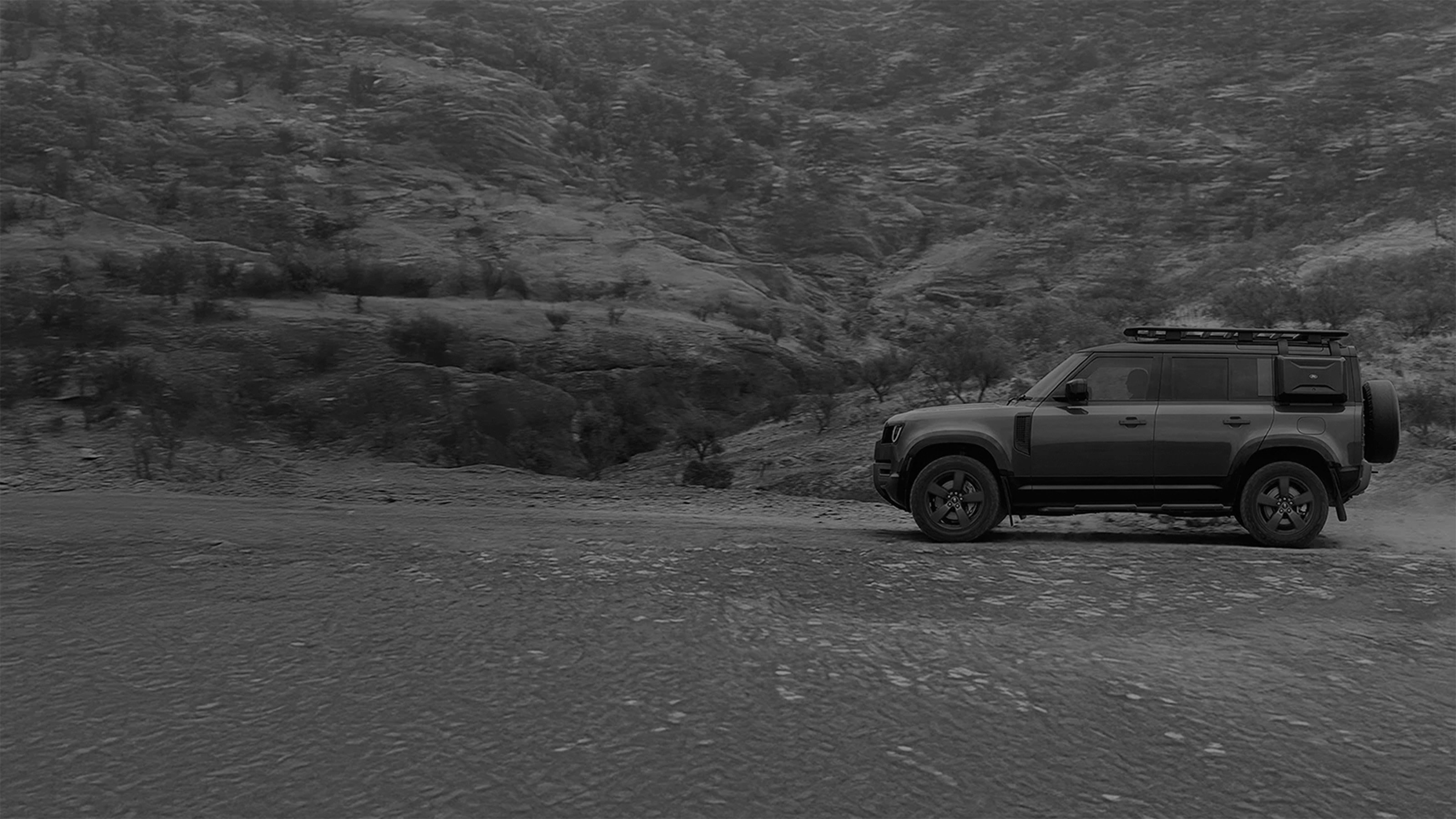 Side view of a Defender driving with promotional text overlay.